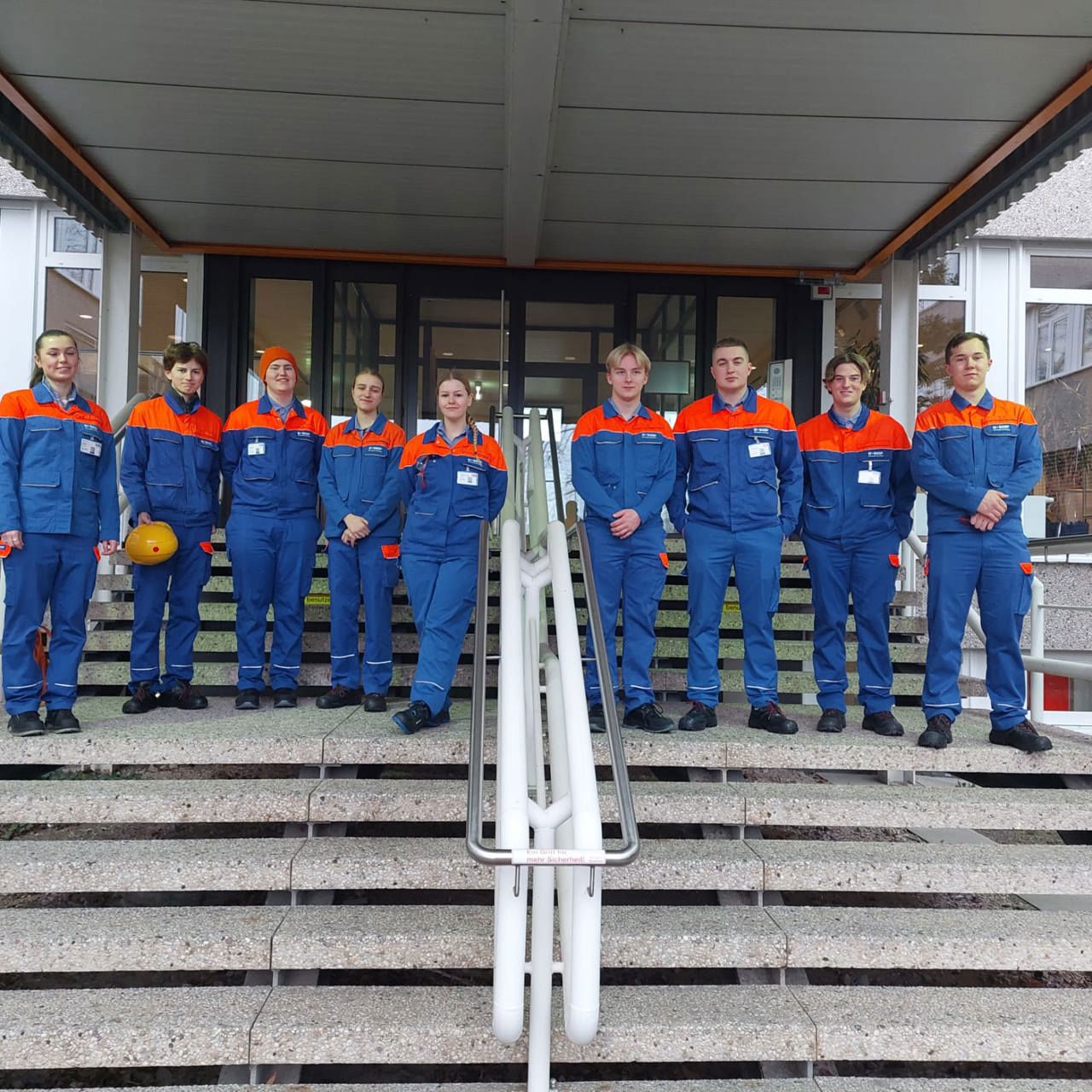 Elevar står på rekke i ei trapp i blå og oransje kjeledresser.kje