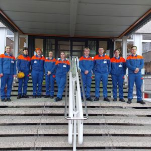 Elevar står på rekke i ei trapp i blå og oransje kjeledresser.kje