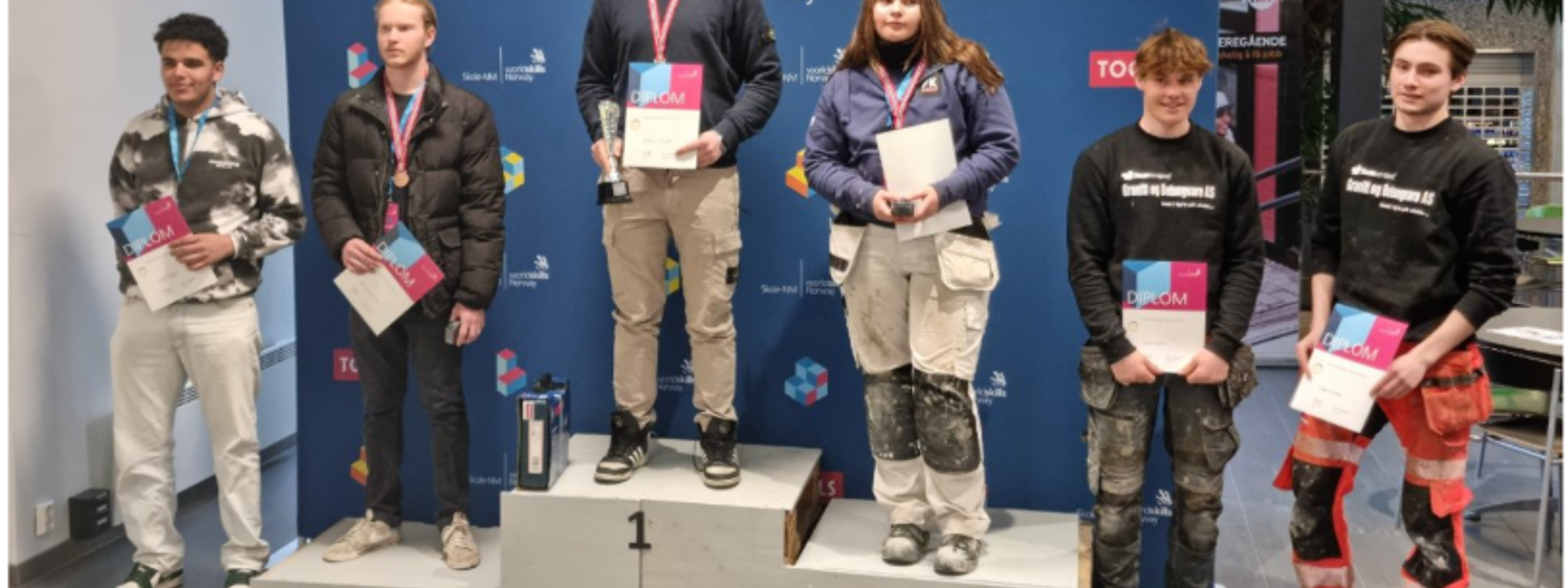 Biletet viser vinnarane av fylkesmeisterskapen i yrkesfag og første plass i Norgesmesterskap for mur- og flisleggjarfaget den 13.04.2023. Her med Andreas Omdahl Ervik i midten på palleplass ved Skogmo VGs i Porsgrunn.